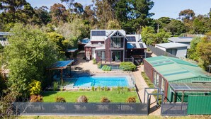 Una propiedad residencial con piscina, paneles solares y jardín cercado.
