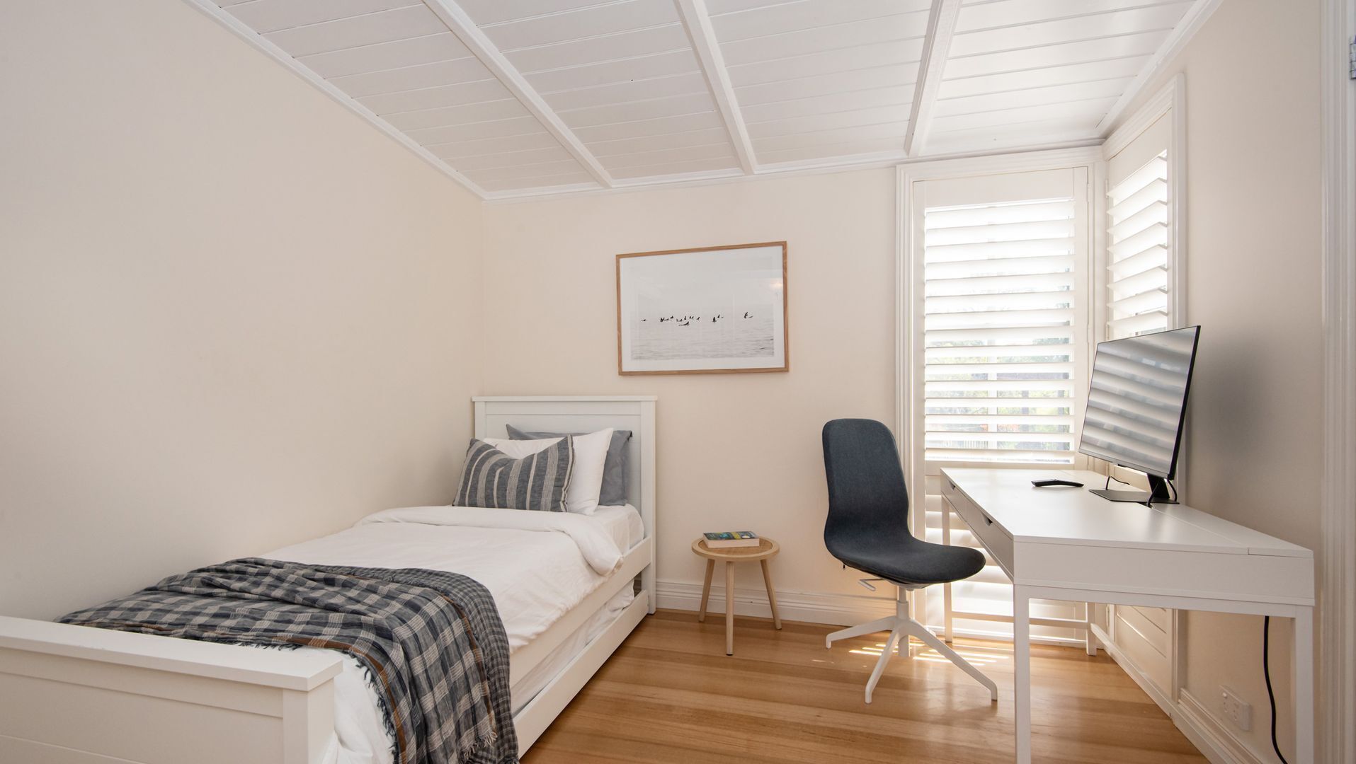 A bedroom with a bed, a desk, and a chair.