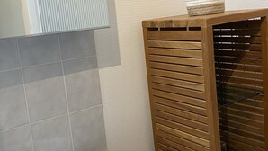 Ein Badezimmer mit einem Holzkosmetikschrank, einem weißen Waschbecken und einem Handtuch auf der Ablagefläche.