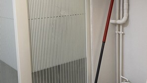 Ein Zimmer mit einem Heizkörper, einem roten Besen und weißen Rohren.