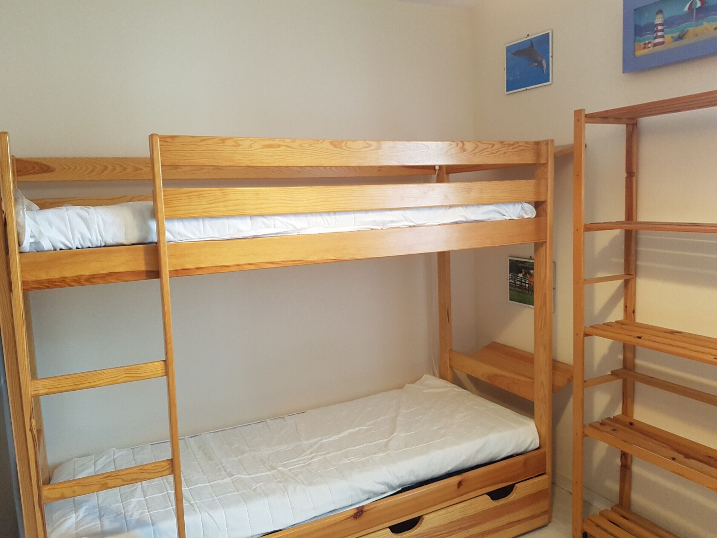 A bunk bed with a wooden frame and white bedding.