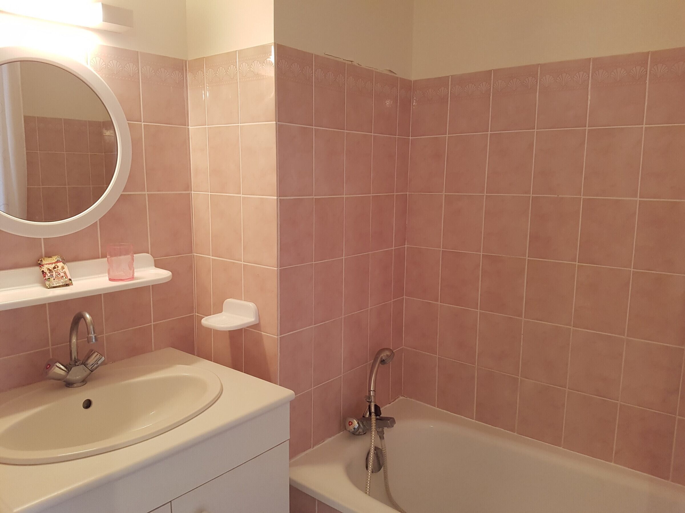 A bathroom with a sink, mirror, and bathtub.