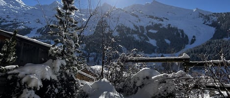 A snow-covered mountain landscape with a clear sky and the sun shining.
