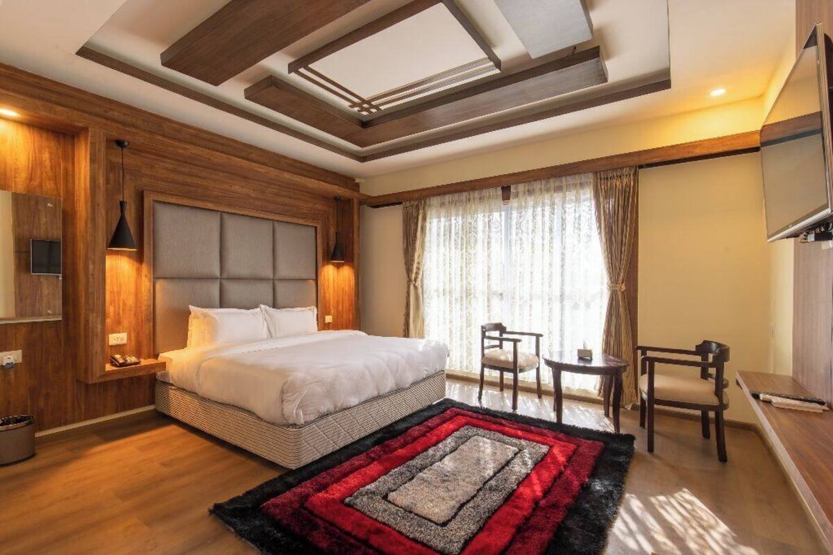 Ein modernes Hotelzimmer mit einem großen Bett, einem Schreibtisch und einem Fernseher.