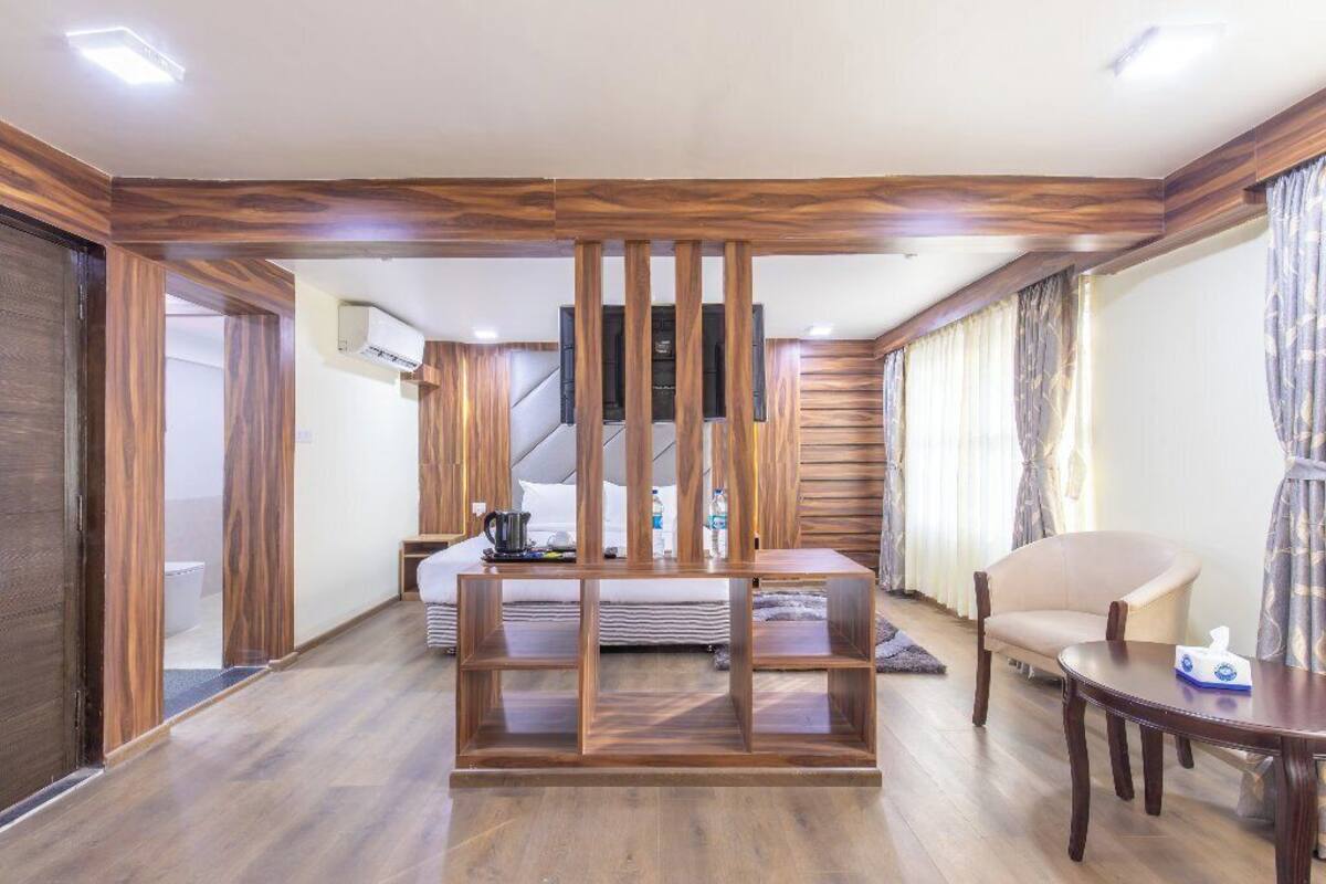 Ein Hotelzimmer mit Holzwand, einem Bett, einem Schreibtisch, einem Stuhl und einem kleinen Tisch.