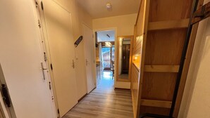 Un couloir avec un plancher en bois, des murs blancs et une étagère en bois sur le côté droit.