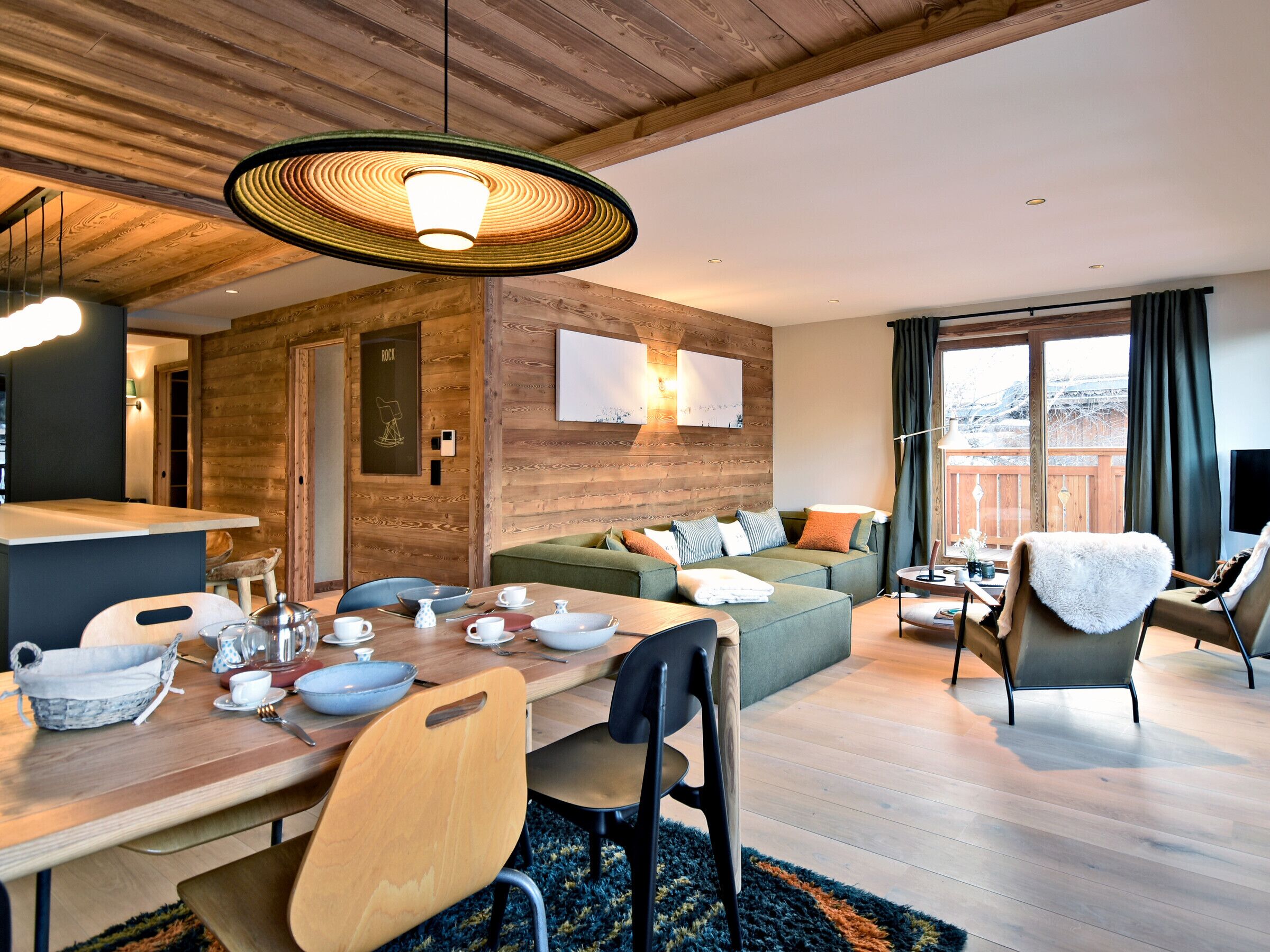 A modern living room with a wooden ceiling, a dining table set with dishes, a sofa, and a chair.