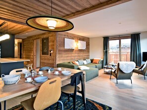 Ein modernes Wohnzimmer mit Holzboden, einem gedeckten Esstisch, einer Couch und einem Sessel.