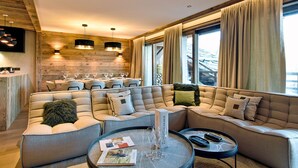 Un salon moderne avec un canapé d’angle, un coin repas et de grandes fenêtres dotées de rideaux.
