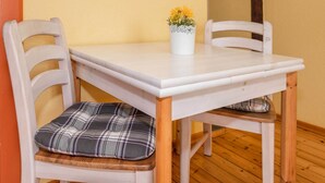 A small dining table with two chairs, a white vase with flowers, and a plaid cushion on one of the chairs. - Modern studio in Zinnowitz with garden - perfect for two! (Zinnowitz)
