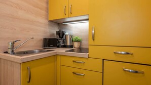 A kitchen with yellow cabinets, a stainless steel sink, a coffee maker, and a small potted plant. - Modern studio in Zinnowitz with garden - perfect for two! (Zinnowitz)