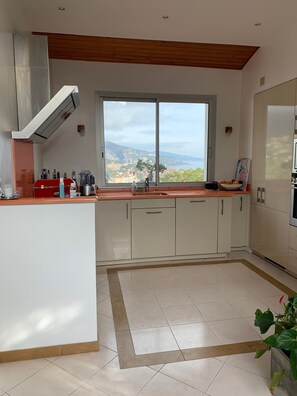 Une cuisine moderne dotée d’une grande fenêtre, de meubles blancs et d’un plafond en bois.