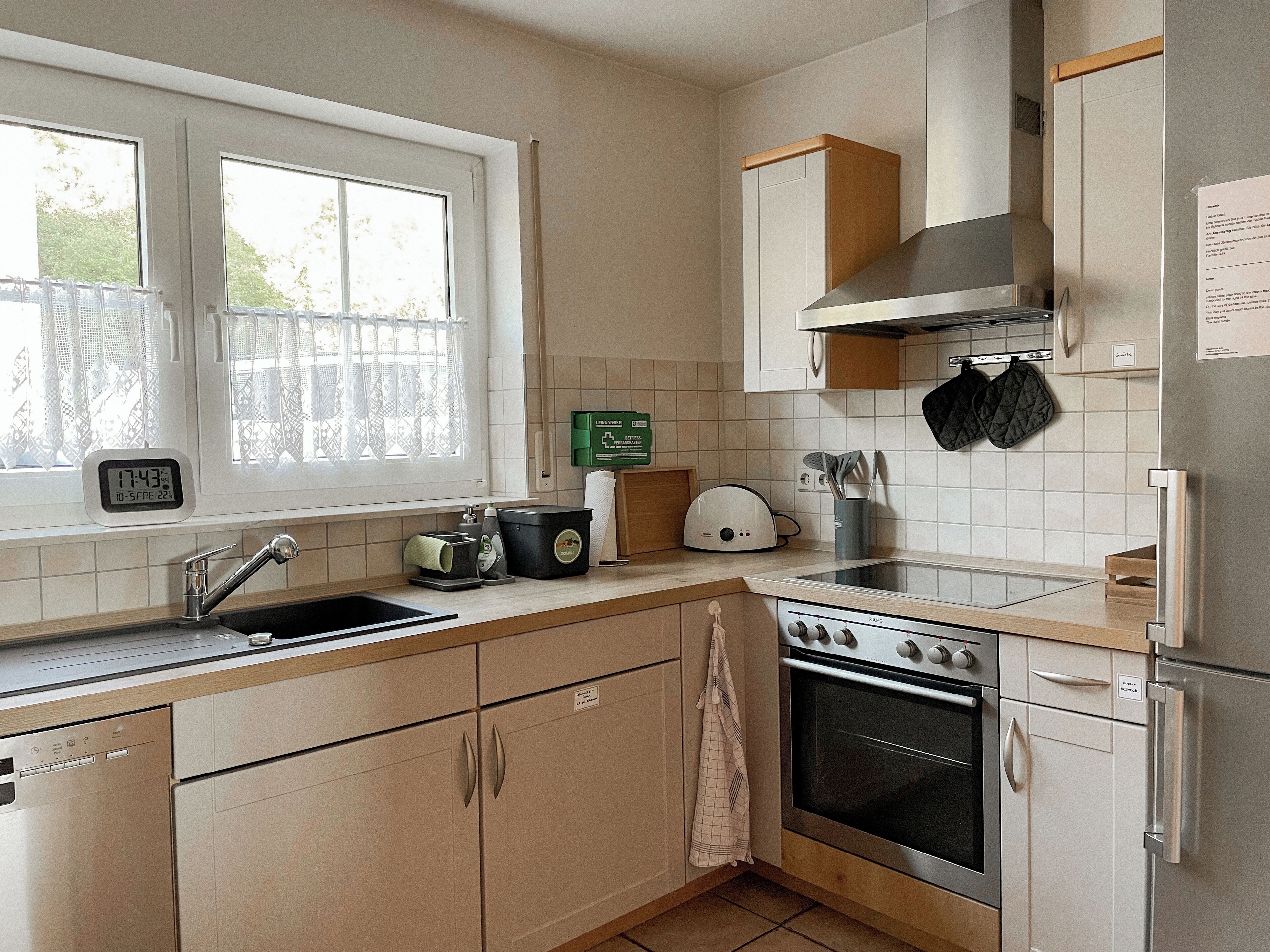 Cocina moderna con pileta, estufa, horno y ventana con cortinas.