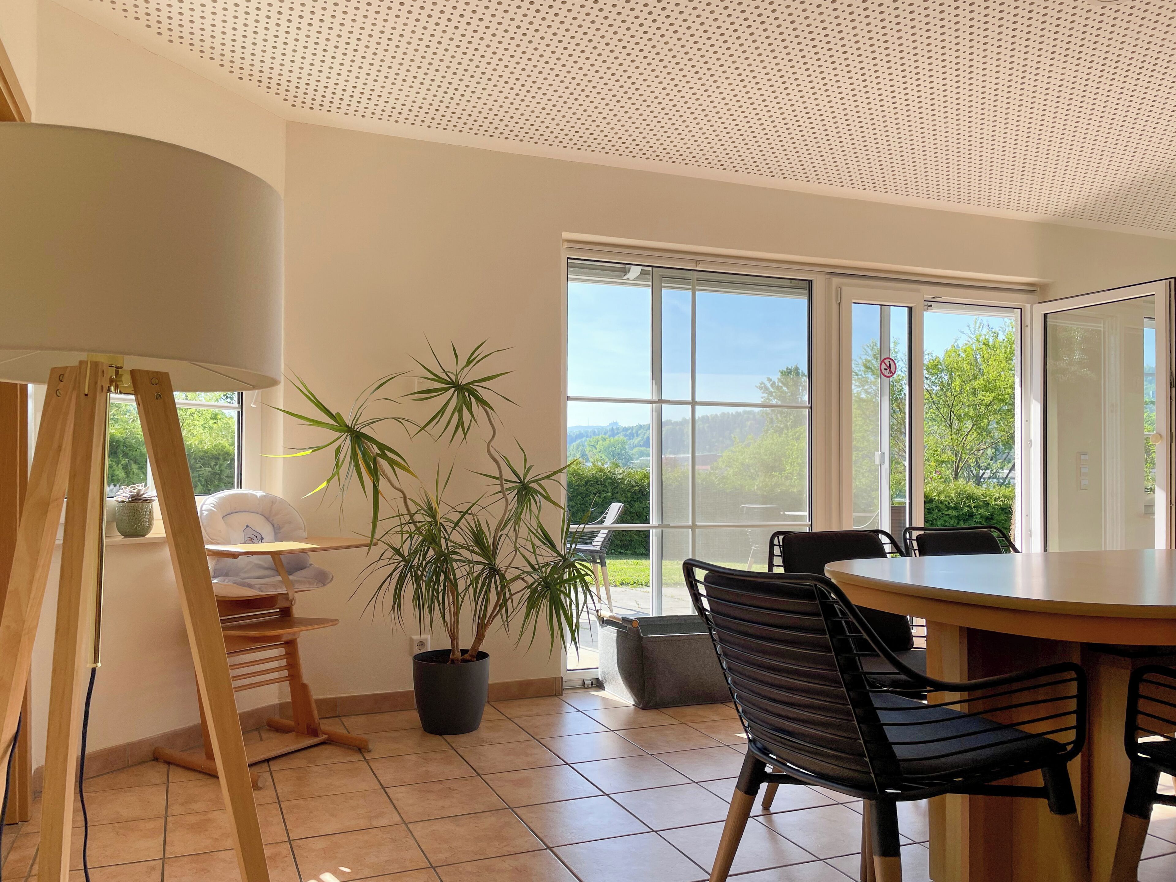A dining area with a large window, a potted plant, and a wooden easel.