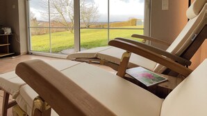 Una habitación con un ventanal grande, un banco de madera y una mesita con una revista.