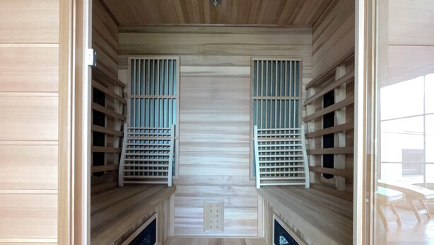 Un sauna con paredes y bancos de madera, sistema de ventilación central y suelo de baldosas.