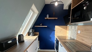 Una cocina moderna con encimeras de madera, microondas integrado y cafetera.