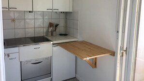 Une cuisine compacte avec des meubles blancs, un lave-vaisselle encastré et un plan de travail en bois.