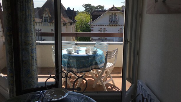 Un balcon avec une table et des chaises, donnant sur un quartier résidentiel avec des maisons traditionnelles.