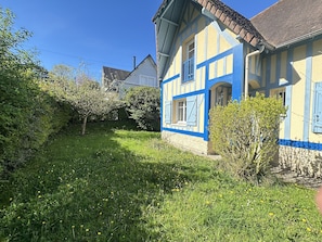 A traditional house with a sloped roof, a chimney, and a well-maintained garden with grass and flowering plants. - Spacious Villa Near Beach and Town Center with Large Private Garden (Villers-sur-Mer)