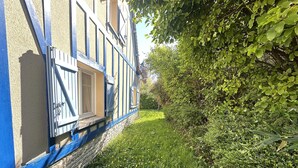 Un bâtiment avec des fondations en pierre, une façade bleue et une fenêtre dotée de volets.