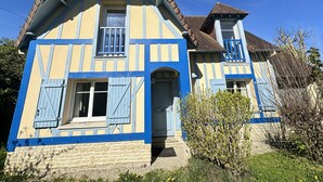 Une maison à deux étages, dotée d’un toit à pignon, d’une porte d’entrée bien visible et d’un petit porche.