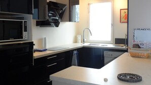 A modern kitchen with a built-in microwave, a sink, and a window providing natural light. - Cabourg: Modern 4/5-room apartment, beach access, 8 ppl, garden and terrace, parking, WIFI (Cabourg)