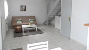 A modern living room with a sofa, a coffee table, and a staircase. - Charming 3-Room Cottage with Private Garden, Near Marina, Sleeps 6, Pet-Friendly, Pool Access (Dives-sur-Mer)