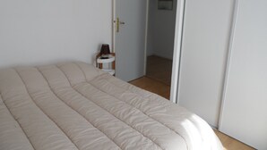 A bedroom with a bed, a nightstand, a door, and a hallway. - Charming 3-Room Cottage with Private Garden, Near Marina, Sleeps 6, Pet-Friendly, Pool Access (Dives-sur-Mer)