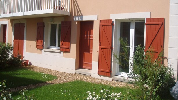 A two-story building with a balcony, red shutters, and a small garden area. - Charming 3-Room Cottage with Private Garden, Near Marina, Sleeps 6, Pet-Friendly, Pool Access (Dives-sur-Mer)