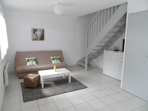 Una sala de estar moderna con un sofá, una mesa de centro, una alfombra y una escalera.