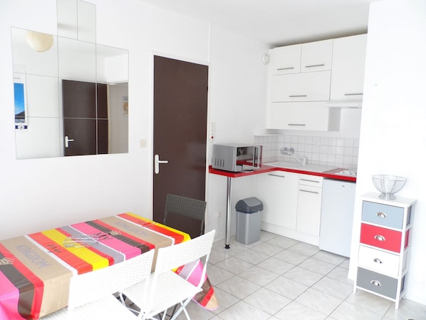 A compact kitchen with white cabinets, a microwave, and a small trash bin.