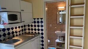 Cocina compacta con microondas, pileta doble y una pequeña mesada.