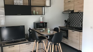 A modern kitchen with a dining area, featuring a microwave, coffee maker, and a flat-screen TV.