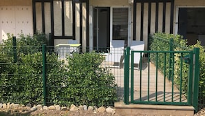 A modern building with a balcony, a gated entrance, and a small outdoor seating area.