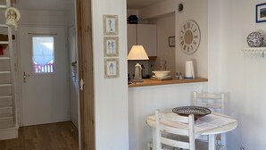 Uma cozinha com um armário de madeira, uma porta branca, uma janela e um relógio de parede.