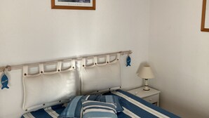 Quarto com cama, mesa de cabeceira, abajur e quadro na parede.