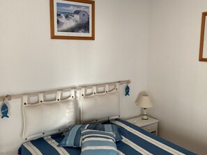 A bedroom with a bed, a nightstand, a lamp, and a framed picture on the wall.