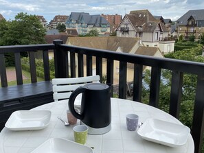 Un balcón con una mesa dispuesta para dos personas, una tetera y dos tazas.