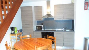 A compact kitchen with a dining table and chairs, a microwave, and a sink. - Duplex 3-Room Apartment Near Beach in Cabourg - Sleeps 6, Parking Included (Le Home Varaville)