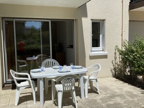 A patio with a white table and chairs, a sliding glass door, and a small window. - Cozy Garden-Level Studio Near Beach in Cabourg – Pet Friendly, Sleeps 4 (Cabourg)