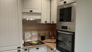 Une cuisine moderne avec des meubles blancs, des appareils en acier inoxydable et un pare-feu en bois.