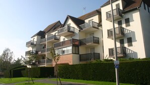 Un immeuble résidentiel à plusieurs étages, doté de balcons, avec un ciel dégagé et une pelouse bien entretenue.