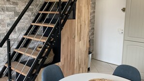 Un intérieur moderne avec un escalier, une porte blanche et une table ronde entourée de chaises.