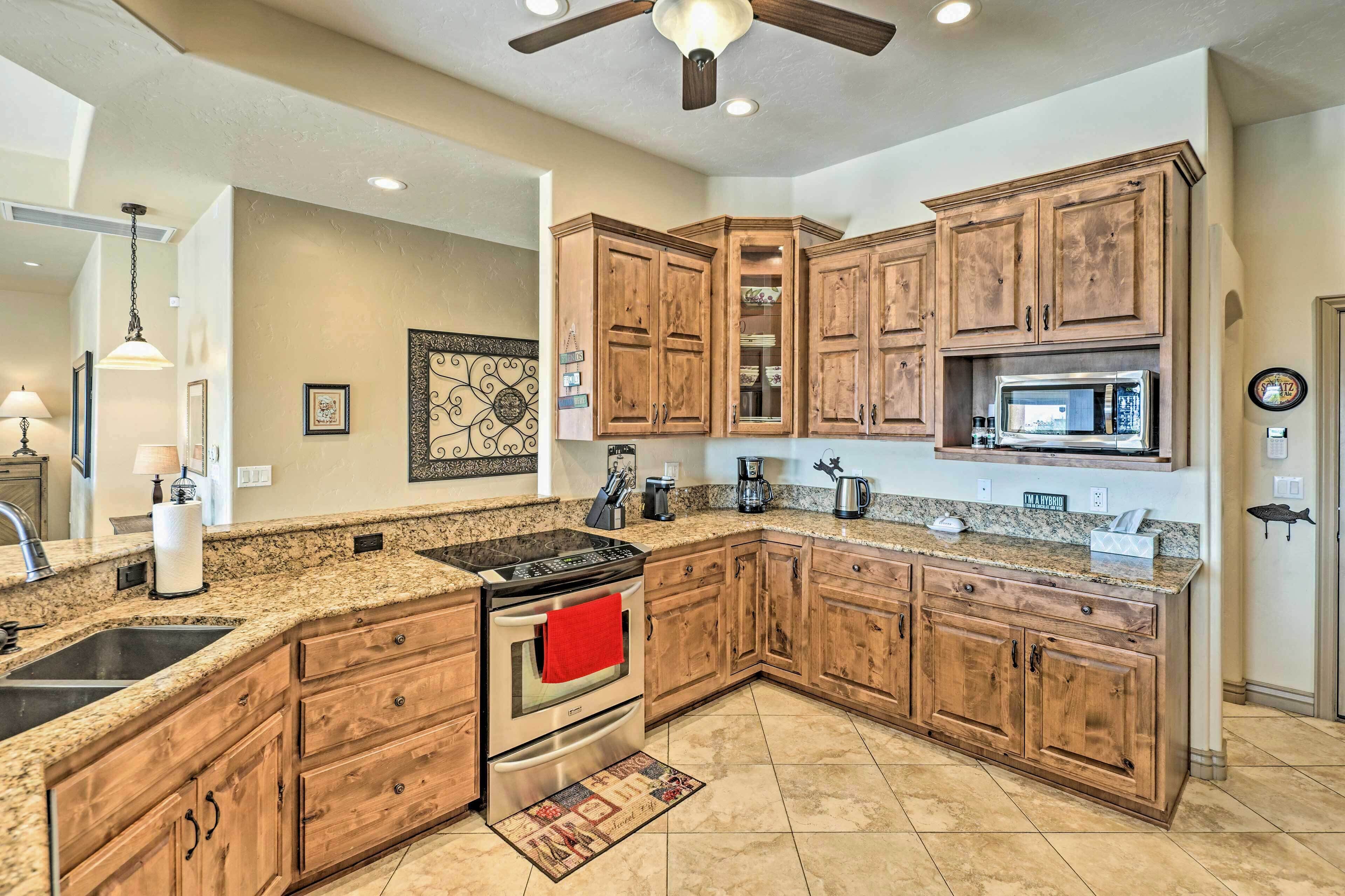 A kitchen with wooden cabinets, granite countertops, a stainless steel stove, and a ceiling fan.