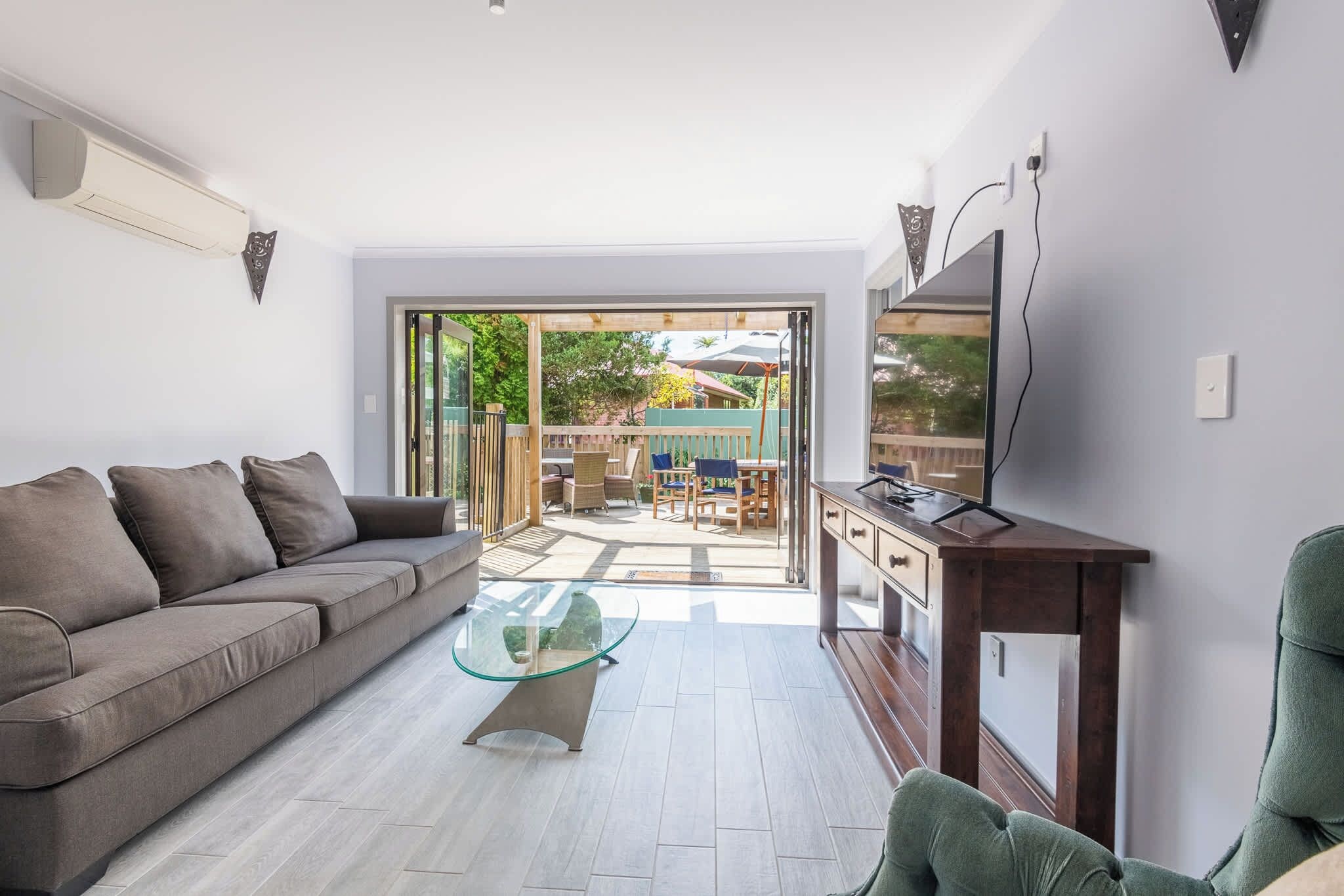 A modern living room with a sofa, a glass coffee table, and a TV on a wooden stand.