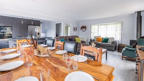 Un salon moderne avec un coin repas, des canapés gris et une cuisine en arrière-plan.