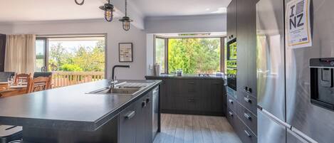 A modern kitchen with a large island, stainless steel appliances, and a view of the outdoors.