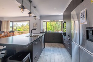 A modern kitchen with a large island, stainless steel appliances, and a view of the outdoors.