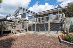 A residential property with a wooden deck, a fenced play area, and a house with large windows.